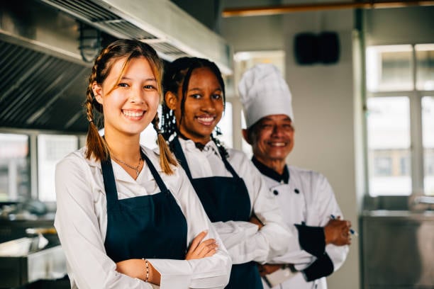 Older kids learning from a chef in a professional kitchen