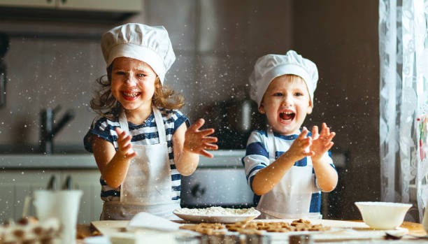 Two young children laughing as they bake together